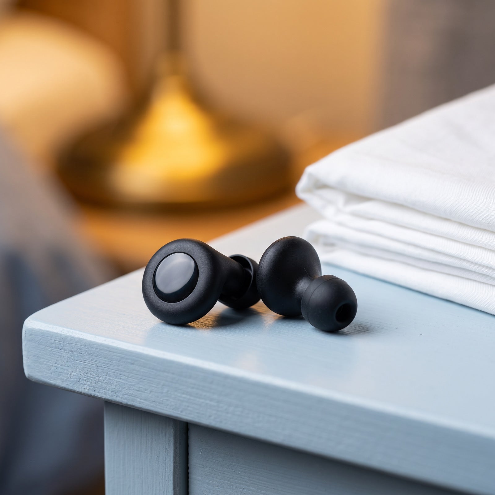 Black Stillday pair on a bedside surface beside folded linen