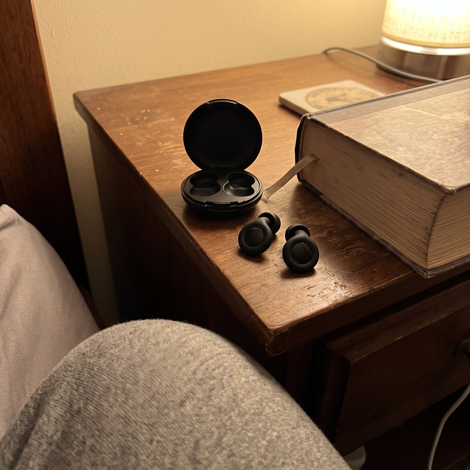 Black Stillday pair and open case beside a bedside book in evening lamplight