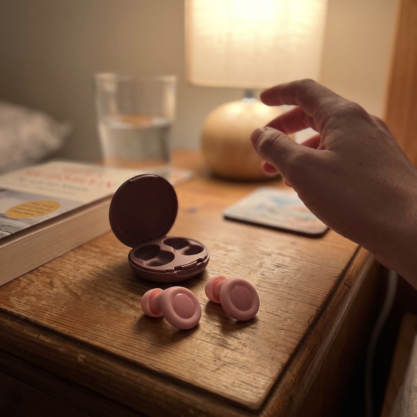 Pink Stillday pair beside its open case as a hand reaches for a reading lamp